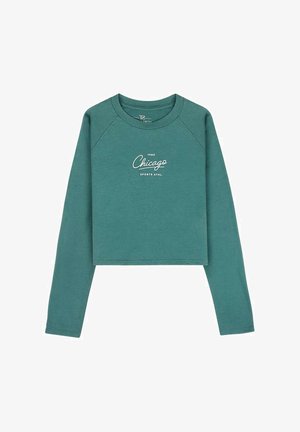 Sweat-shirt court à manches longues couleur sarcelle avec le texte "1989 Chicago Sports Athl." imprimé en blanc au centre devant.