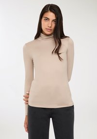 Maglione beige a collo alto con maniche lunghe, design aderente, realizzato in un materiale morbido e elastico. Il collo è alto e senza cuciture.