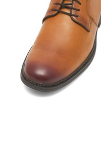 Brązowe skórzane buty eleganckie z okrągłym noskiem, sznurowane, z kontrastującą ciemnobrązową podeszwą i widocznym szwem wzdłuż krawędzi.