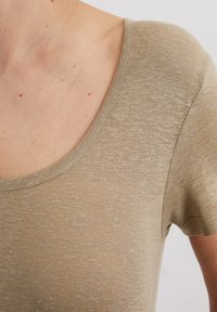 Beige gebreide stof T-shirt met een ronde hals en korte mouwen, met een zachte textuur en subtiele kleurvariaties.