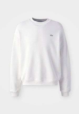 Sudadera blanca de algodón con cuello redondo, puños acanalados, dobladillo acanalado y un pequeño logotipo bordado en el pecho. Textura suave.