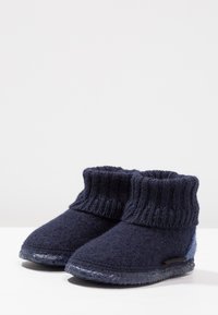 Donker marineblauwe wollen enkellaarsjes met een geribbelde gebreide boorden, een zachte textuur aan de bovenkant en een stevig zwart rubberen zool, met een klein rood accentdetail.