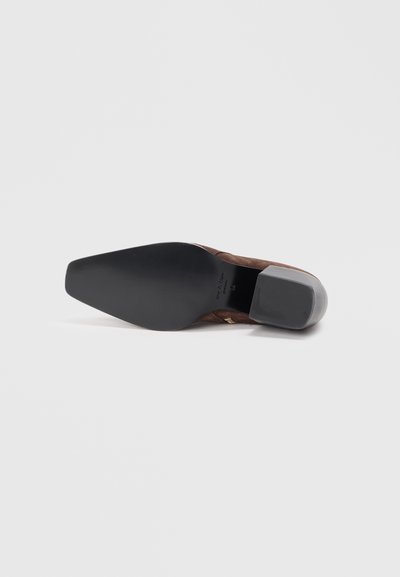 Chaussure en suede marron avec un bout pointu, un dessus texturé, un petit talon bloc et une semelle extérieure en caoutchouc noir lisse. Aucune marque visible.