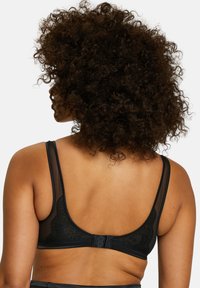 Zwarte kanten beha met doorzichtige gaaspanelen, voorzien van verstelbare bandjes en een haak-en-oogsluiting. Soepele textuur met bloemmotieven.