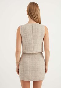 Beige tweedklänning med kort topp och åtsittande minikjol. Tyget har ett strukturerat rutmönster och en sömdetalj bak.