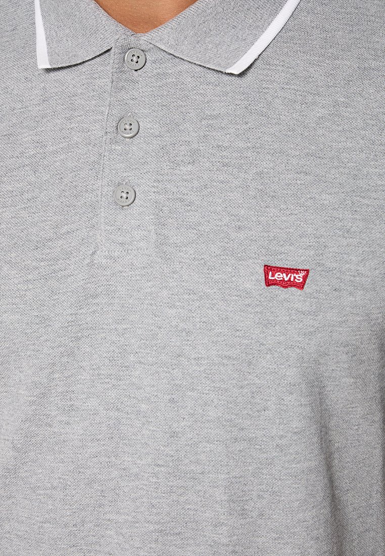 Polo gris en coton texturé, avec un col bordé de blanc, trois boutons gris et un patch logo Levi's rouge sur la poitrine.