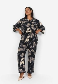 Black blouse and wide-leg pants set featuring a beige and grey abstract pattern, with relaxed fit and three-quarter sleeves.