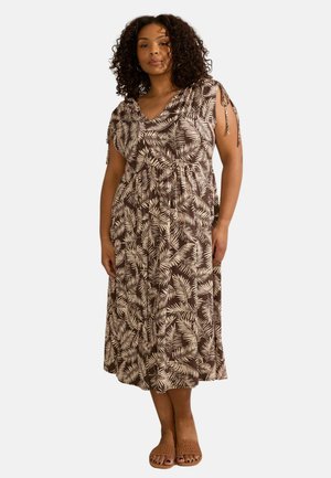 Braunes Kleid mit einem blättrigen weißen Muster, kurzärmeligen, taillierten Schnitt und Knöchellänge. Getragen mit tanfarbenen, strukturierten Sandalen.