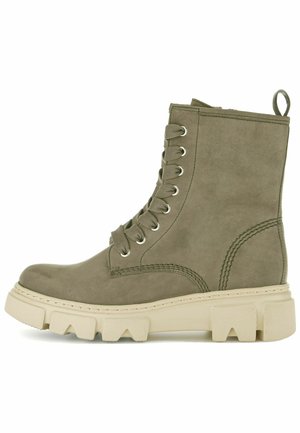 Bottine en suede vert olive avec un bout arrondi, un laçage sur le devant, des œillets en argent et une semelle en caoutchouc beige épaisse avec un motif de semelle rugueux.