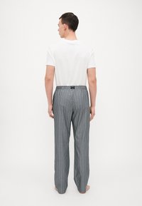Gestreepte pyjamabroek met een elastische tailleband, gemaakt van lichtgewicht stof in tinten grijs, met dunne verticale lijnen en een relaxte pasvorm.