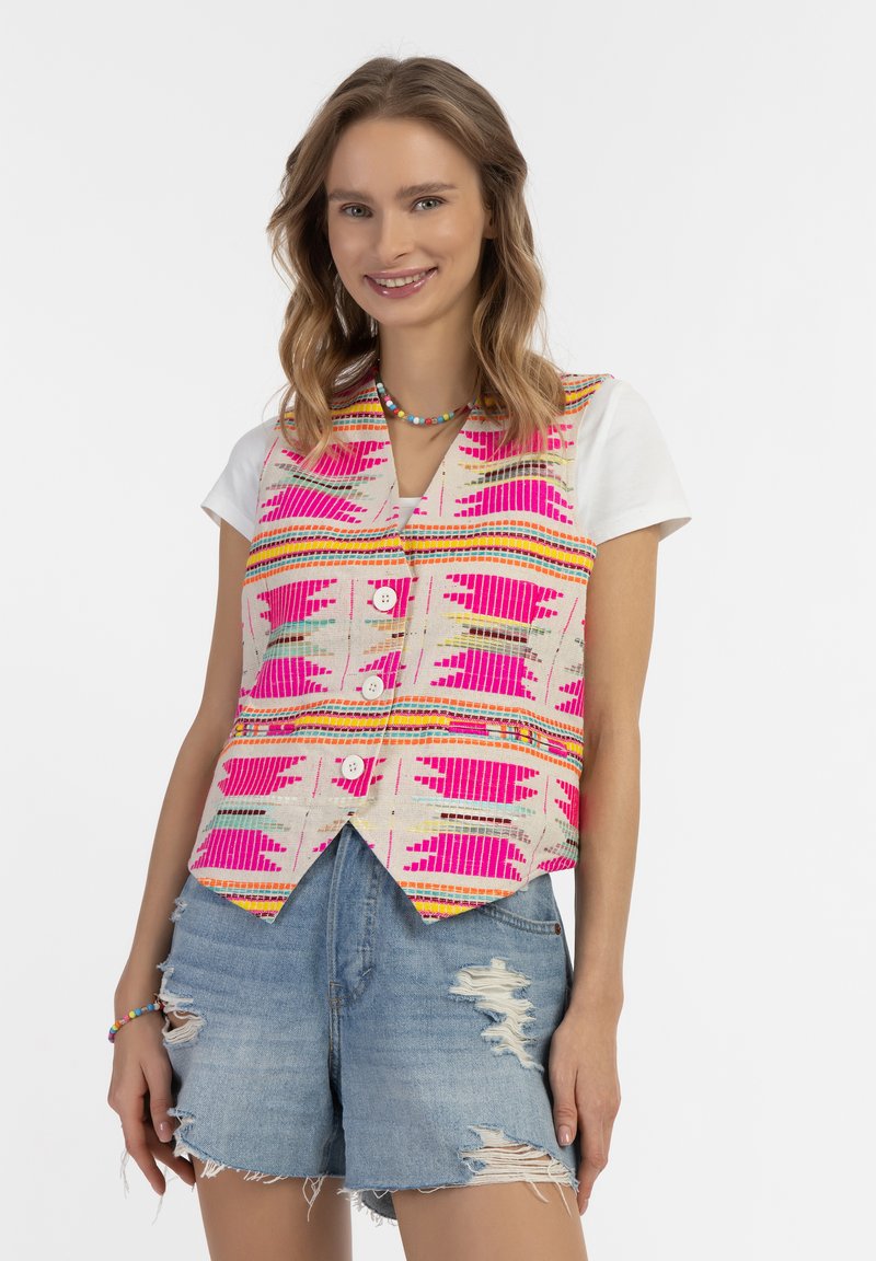 Colorful vest with geometric patterns in pink, yellow, and beige, featuring a v-neckline and three-button closure, paired with distressed denim shorts.