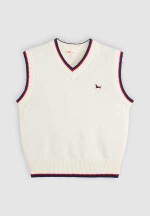 Hvit strikket ermeløs genser med marineblå og rød kant, samt en liten brodert brun dachshund på brystet.