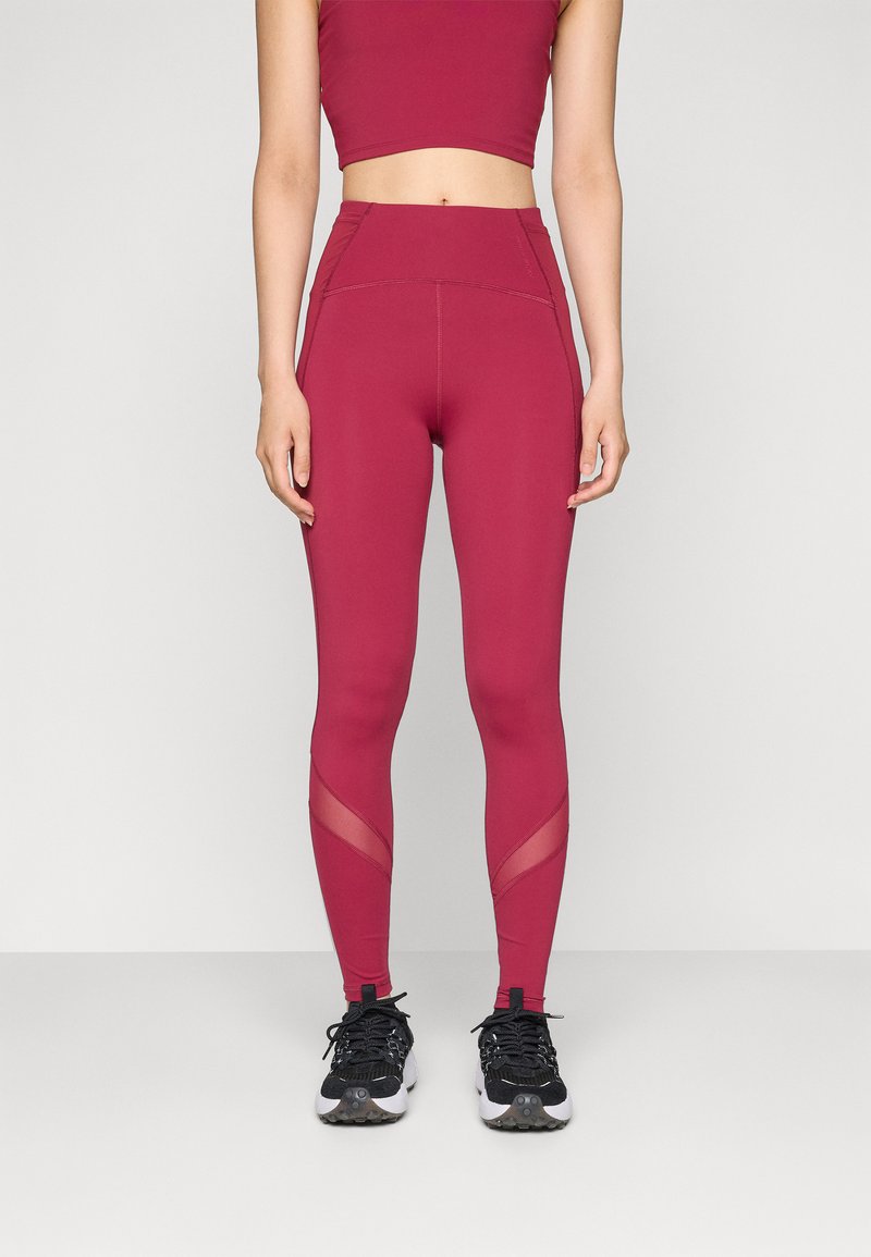 High-waisted maroon leggings with a smooth texture, mesh panels at the calves, and a fitted design, paired with black athletic shoes.