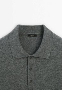 Graues, gestricktes Polohemd mit klassischem Kragen, fünf schwarzen Knöpfen und einer weichen Textur. Das Etikett ist im Halsbereich sichtbar.