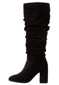 Svarta knähöga stövlar i mjuk mocka, med en slouchad design, rund tå och en kraftig klack. Slät textur med minimala accenter.