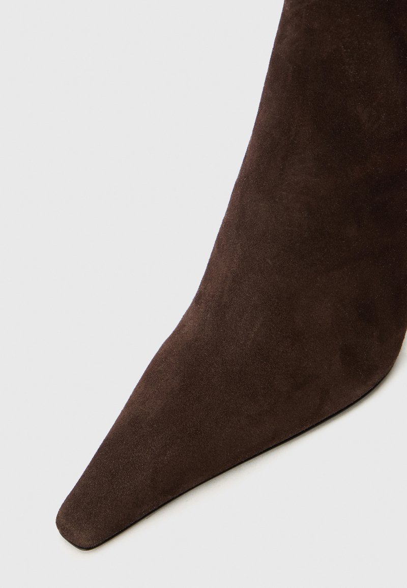 Brune ruskinds ankelstøvle med spids tå og glat tekstur, der har et tætsiddende design for en strømlinet silhuet.