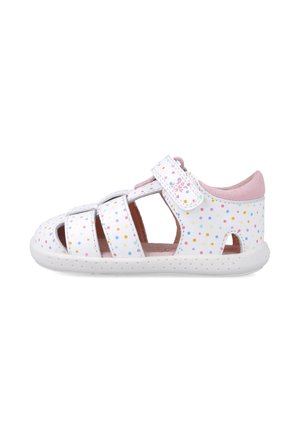 Sandal blanco con lunares de colores, tres correas y cierre de velcro. Presenta un forro acolchado rosa y una suela blanca texturizada.