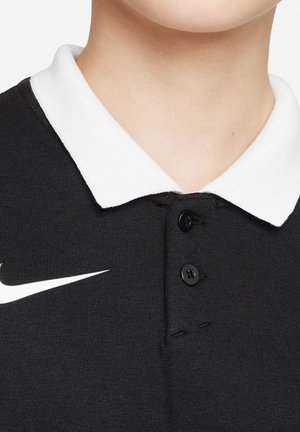 Schwarzes Polo-Shirt mit einem weißen Kragen, ausgestattet mit drei schwarzen Knöpfen und einem auffälligen weißen Nike-Logo auf der linken Seite. Glatte Stoffstruktur.