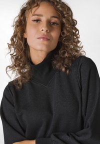 Felpa nera con collo alto, tessuto testurizzato e vestibilità rilassata. Presenta spalle abbassate e un design minimalista.