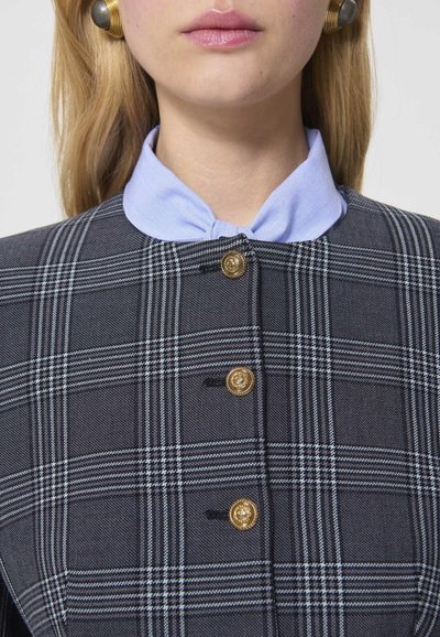 Jachetă în carouri cu un model gri și albastru, având butoane aurii și un guler de un albastru deschis. Materialul are un finisaj texturat.
