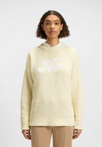 Maglione giallo lavorato a maglia con orlo a coste. Presenta un logo bianco "Hugo" sulla parte anteriore e un design con spalla cadente. Tessuto testurizzato con vestibilità ampia.