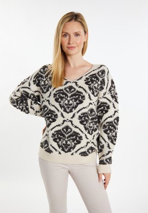 Strickpullover mit V-Ausschnitt, der ein schwarzes Blumenmuster auf einem cremefarbenen Hintergrund zeigt. Langärmlig mit geripptem Saum.