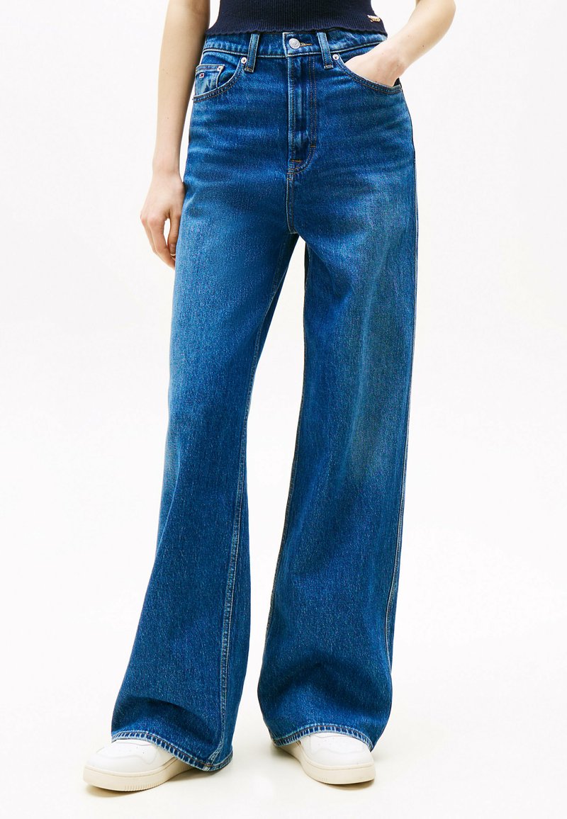 Jeans de mezclilla azul de talle alto con un diseño de pernera ancha, que presentan un estilo clásico de cinco bolsillos y un ligero desgaste a lo largo de las costuras.
