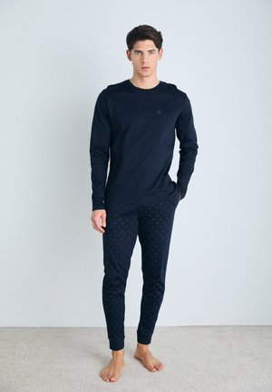 Chemise à manches longues bleu marine foncé avec un col rond, associée à un legging à motifs assortis comportant de petits points. Le tissu semble doux et extensible.