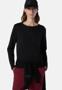 Maglietta nera a maniche lunghe con il logo "NORTH SAILS" in stampa scura sul petto, abbinata a pantaloni bordeaux con dettagli del logo coordinati.