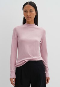Helles rosa Langarmoberteil mit hohem Kragen, aus einem glatten, weichen Stoff. Verfügt über gerippte Bündchen und einen leicht lockeren Schnitt.