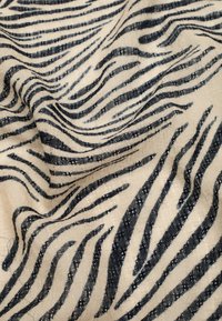 Leichter Stoff mit einem schwarz-weißen gestreiften Muster, das einem Zebradruck ähnelt, mit sanfter Drapierung und einer leicht strukturierten Oberfläche.
