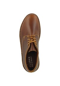 Chaussure Clarks Originals en cuir marron, avec un bout arrondi, un design à lacets et des coutures visibles le long du bord de la semelle.