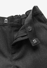 Pantalon gris foncé avec fermeture éclair, bouton et agrafe métallique le long de la ceinture.
