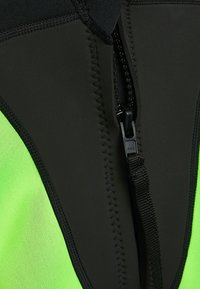 Fekete és neon zöld búvárruha texturált anyagból, elöl cipzárral és megerősített varrással a varratok mentén.