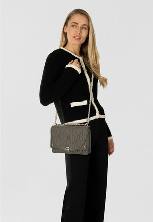 Gray leather handbag with a textured pattern, silver hardware, and a chain strap, worn over a black and white cardigan.