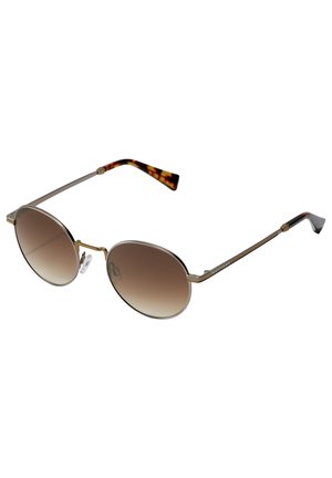 Lunettes de soleil rondes avec des verres dégradés marron à deux tons, monture en métal et branches en acétate écaille de tortue à motif. Équipées de plaquettes de nez transparentes pour plus de confort.
