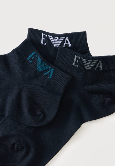 Trois paires de chaussettes noires aux chevilles avec un logo comprenant les lettres E et A et un symbole d'aile stylisé en blanc, bleu et gris.