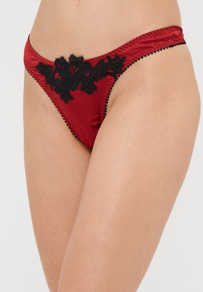 Punane satiinist string aluspüksid musta pitsist detailiga ees ja ääristuses. Omab lillemustri ja kontrastset tekstuuriga servi.