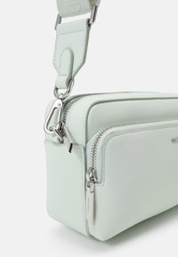 Borsa a tracolla in ecopelle verde chiaro con zip argentate, tracolla rimovibile e design rettangolare compatto.