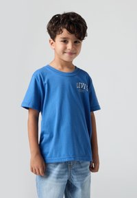 Modré bavlněné tričko s krátkým rukávem, kulatým výstřihem a logem Levi's na přední straně. V kombinaci se světle modrými džínami.