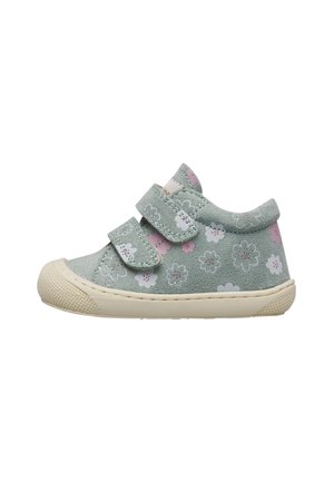 Chaussure verte pour tout-petit avec des motifs de fleurs roses et blanches, deux brides ajustables en Velcro, et une semelle en caoutchouc texturée de couleur crème.