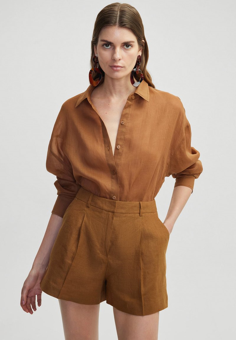 Brown, lightweight button-up shirt with a collar and rolled sleeves, paired with matching high-waisted shorts. Textured fabric detail.