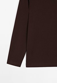 Dark brown long sleeve shirt sleeve and bottom hem on a white background, showing fabric texture and stitching details.