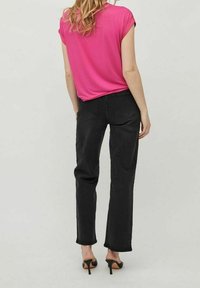 Jeans in denim nero con taglio dritto, abbinati a un top corto a maniche corte di un vivace colore rosa. Design elegante e texture morbida. Scarpe nere con tacco alto.