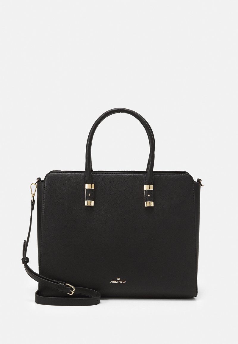 Sac à main structuré noir avec double poignée, bandoulière amovible, ferrures dorées et petit logo de marque sur le devant.