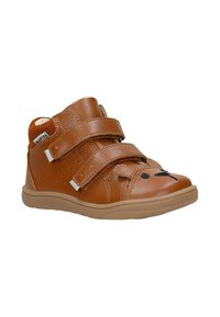 Chaussure enfant en cuir marron avec deux brides Velcro et un motif tête d’ours noir sur l’avant, présentée sur fond blanc.