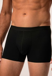 Boxer shorts neri realizzati in tessuto liscio e elasticizzato. Presentano una cintura spessa con un marchio discreto e un design aderente a metà coscia.