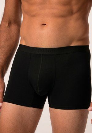 Boxers noirs fabriqués en tissu lisse et extensible. Présentent une taille épaisse avec un branding subtil et un design ajusté mi-cuisse.