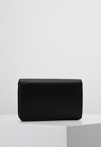 Czarna skórzana torebka o prostokątnym kształcie, gładkiej fakturze i zamknięciu na klapę. Brak widocznych elementów metalowych lub wzorów. Prosty i elegancki design.