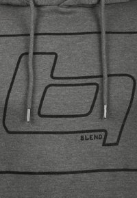 Grijze stof met zwarte abstracte geometrische lijnen en het woord "BLEND," met twee trekkoorden met metalen uiteinden.